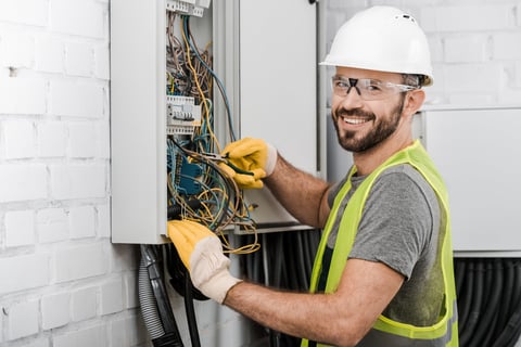 Smiling electrician repairing electrical box